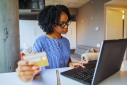 Mujer consultando cuentas bancarias sin comisiones con una tarjeta en la mano.